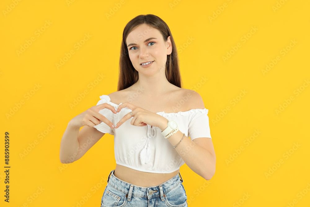 Wall mural Attractive young girl shows heart with hands