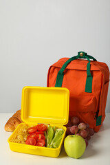 Lunch boxes with food and a school backpack