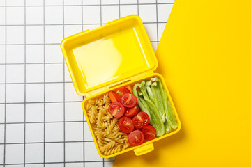 Yellow lunch box with food on a light background