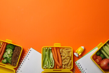 Yellow lunch box with delicious food and school supplies