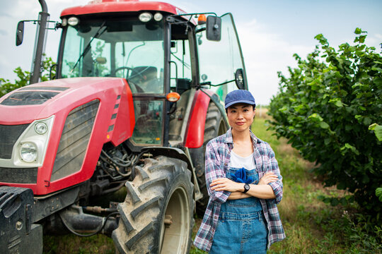 Portrait of a Asian female farmer with tractor in orchard
