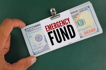 dollar bills and white paper with the word EMERGENCY FUND. concept of emergency money