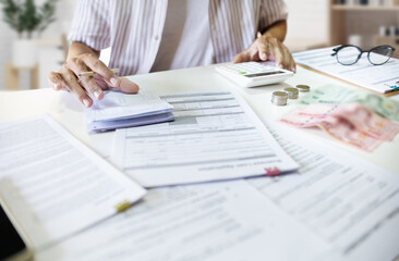 Asian man with many document on desk checking passbook calculate cost of starting a business and apply for loan approval.