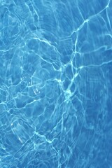 Blue water with ripples on the surface. Defocus blurred transparent blue colored clear calm water surface texture with splashes and bubbles. Water waves with shining pattern texture background.