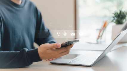 Businessman using a smartphone and touching on virtual screen contact icons, Contact us or Customer...