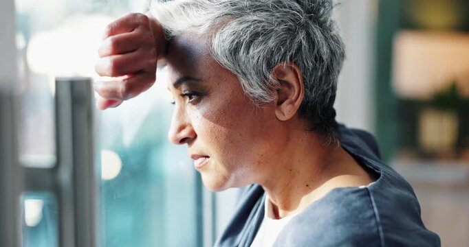 Woman, doctor and stress with thinking by window for deadline, healthcare burnout and fatigue in hospital. Mature medic, mental health and tired with depressed thoughts, patient death and overworked