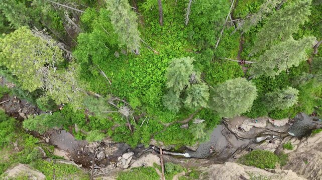 Drone view above people sliding in the Devils Bathtub waterfall and pool in Spearfish Canyon, South Dakota