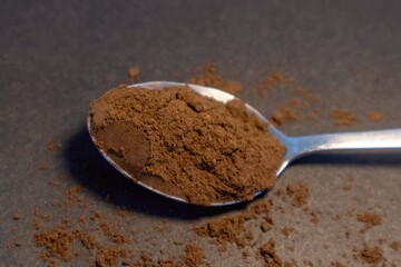 Сoffee powder on the spoon isolated on dark background