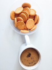 A cup of hot milk coffee accompanied by delicious biscuits on a white background