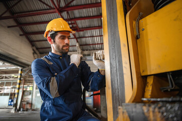 man in a blue work suit is fixing a forklift