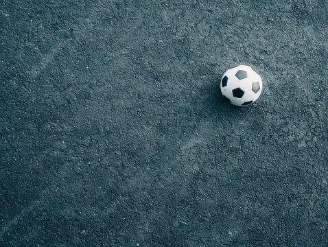 Soccer ball on rough asphalt surface, captured from above, isolated for sports and outdoor recreational themes.