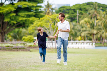 Fototapeta premium Man piggyback his son on a shoulder and walking around the park.