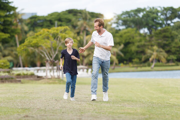 Fototapeta premium Man piggyback his son on a shoulder and walking around the park.