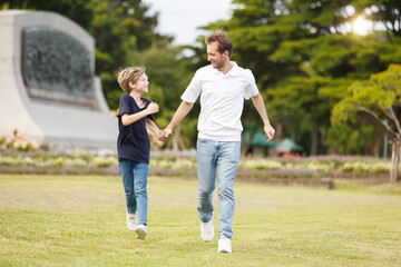 Man piggyback his son on a shoulder and walking around the park.