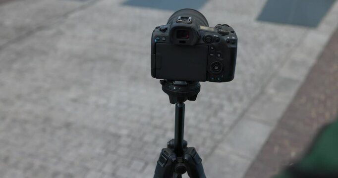 Person adjusting a mirrorless camera on a tripod, camera video, photo equipment.
