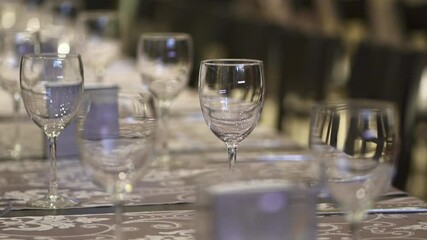 An elegant restaurant with numerous tables set, featuring chairs and wine glasses ready