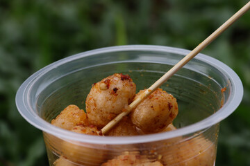 Cipak Koceak, a crispy and chewy tapioca snack from Garut, West Java, Indonesia. Served in a white plastic container with a spicy chili sauce. Perfect for showcasing traditional Indonesian cuisine.