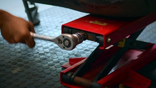 Mechanic using a Scissor Jack with Lift for Motorcycle to remove the wheels in garage, Maintenance and repir motorcycle service concept,  