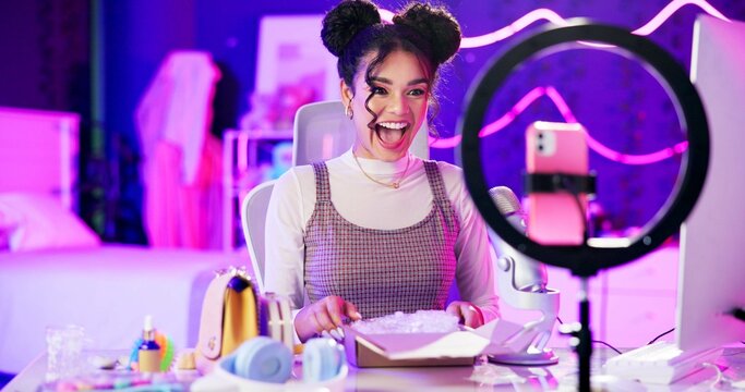 Unboxing, live stream and happy influencer woman with microphone, neon light and makeup in home studio. Content creator, beauty streamer or excited girl in online video for skincare product review