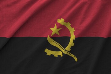 Angola flag depicted on folded wavy fabric of old cloth close up