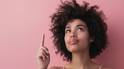 Obraz premium Elegant female model pointing up, pink backdrop studio photo