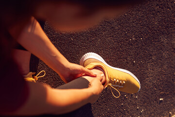 Young woman with ankle and leg pain during jogging and exercise in urban park.