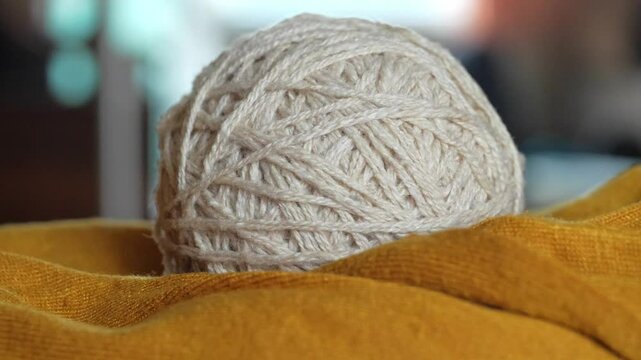 A ball of white yarn lies on the fabric close-up