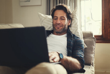 Laptop, smile and man in home for remote work, reading email and social media. Computer, relax and freelance journalist in living room for writing article, research report or news on internet on sofa