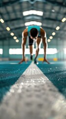 Obraz premium Athlete getting ready for a sprint in an indoor track, focusing on start position and determination. Blurred background for emphasis.