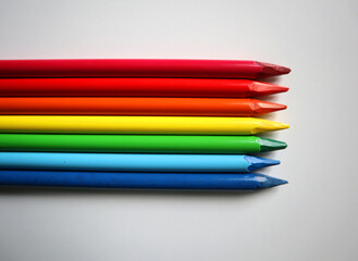 Fototapeta premium Photo of colored pencils arranged in the colors of the rainbow on white background. Pencils without wood. Pencils are placed in the middle, horizontally. Go beyond the background on the left side.