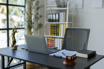 Image of a lawyer's desk, contract documents, hammer, statue of the Goddess of Justice. Laptop on table in office, law, legal services, advice, justice and legal concepts.