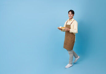 Happy barista asian man serving customer holding coffee cup at coffee shop isolated on blue copy space background.