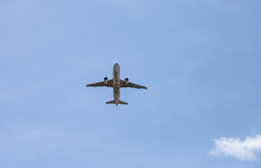Airplane flying in blue sky, bottom view. Passenger plane at flight, travel concept