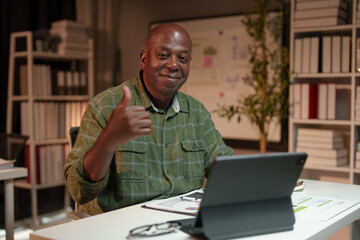 Happy African American man looking at laptop computer screen, typing, searching for information, checking email, chatting on social network. Freelance blogger working on online projects.