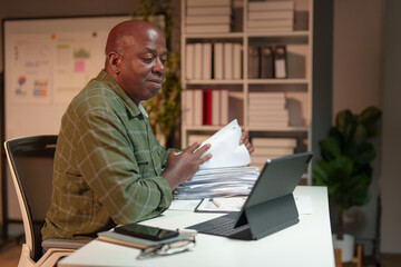 Retired businessman, personal business is checking, checking documents, searching for financial reports. Analyze online data in the office Sitting at the desk in front of the laptop.