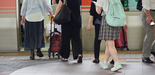 夏の駅のホームで電車に乗る通勤通学の人々の姿