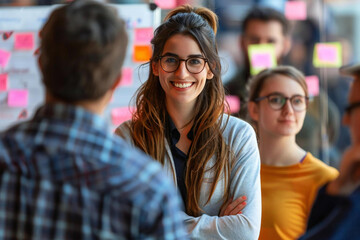 Naklejka premium The beautiful young woman with long brown hair and glasses is smiling and explaining Scrum Agile Sticky to a diverse group of people, including a middle-aged man with a well-groomed beard