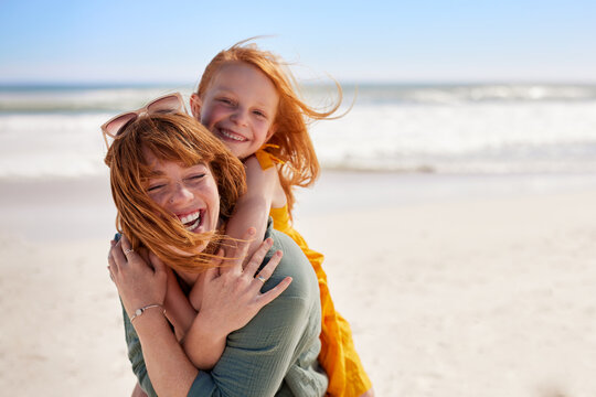 Joyful young mother smiling with little daughter at beach
