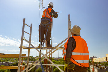 Boss oversees construction worker as binding rebar for reinforce concrete column at the building...