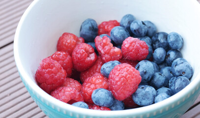 Fresh berries in ceramic bowl. Blueberries and raspberries. Healthy Lifestyle. Nature and harvest in summer. 