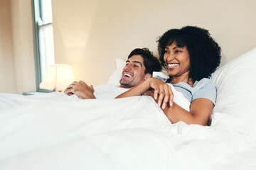 Couple, happy and watching tv in bed at house for relax, love and wellness together with trust,...