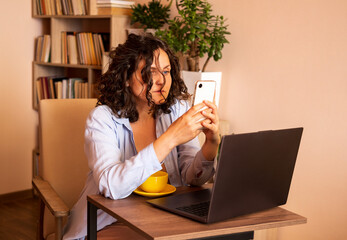 Young woman using laptop and mobile phone at the working space.