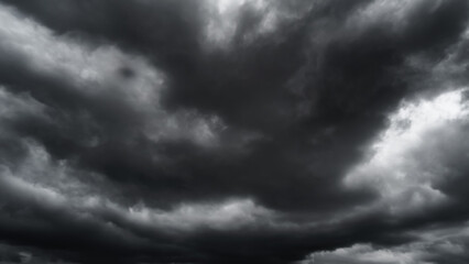 Fototapeta premium dark dramatic sky with black stormy clouds before rain or snow as abstract background, extreme weather, the sun shines through the clouds, high contrast photo