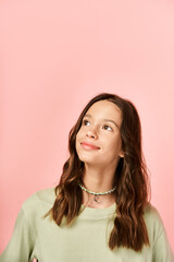 A fashionable teenage girl strikes a pose in front of a brightly colored pink wall with confidence and style.