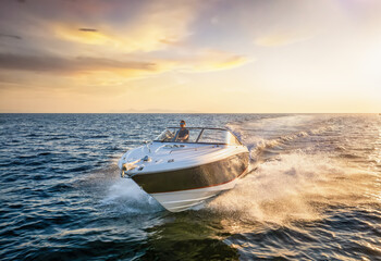 Front view of a sports motor boat cruising with high speed over the blue sea during summer sunset...