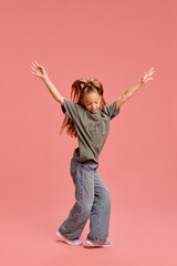 Full-length portrait of happy young girl, child in casual t-shirt and jeans, cheerful dancing and...