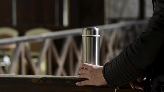 Closeup view of woman closing lid of thermo bottle in winter
