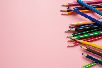 A row of colorful pencils on a pink background