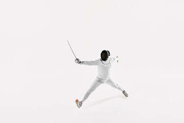 Fencer wearing white suit and mask in mid-air, with their rapier pointed ahead and their body stretched out in jump against white studio background. Concept of sport, competition, achievement. Ad