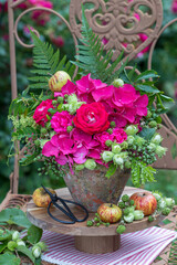 Blumen-Arrangement mit pink Rosen, Hortensienblüten, Haselnüssen, Brombeeren und Blättern in einem vintage Terracotta-Topf 